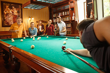 Image showing Young men and women playing billiards at office after work.