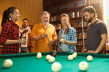 Image showing Young men and women playing billiards at office after work.