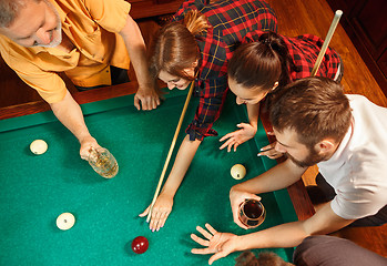 Image showing Young men and women playing billiards at office after work.