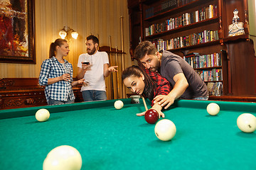 Image showing Young men and women playing billiards at office after work.