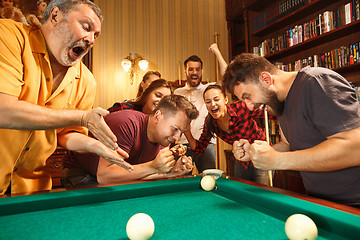 Image showing Young men and women playing billiards at office after work.