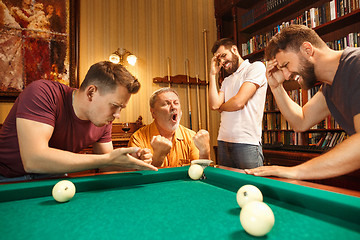 Image showing The displeased men playing billiards at office after work.