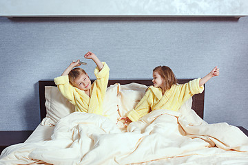 Image showing Happy laughing kids, boy and girl in soft bathrobe after bath play on white bed