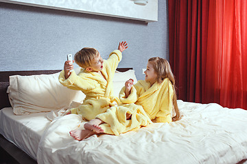 Image showing Happy laughing kids, boy and girl in soft bathrobe after bath play on white bed