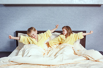 Image showing Happy laughing kids, boy and girl in soft bathrobe after bath play on white bed