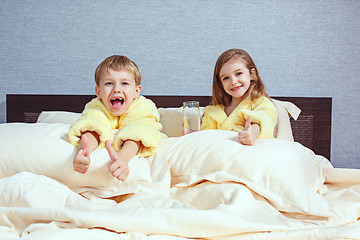 Image showing Happy laughing kids, boy and girl in soft bathrobe after bath play on white bed