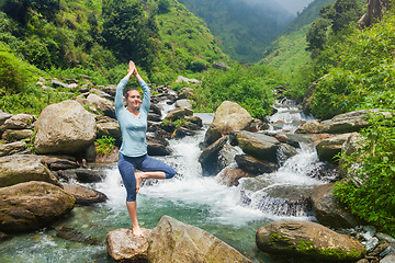 Image showing Woman in yoga asana Vrikshasana tree pose at waterfall outdoors