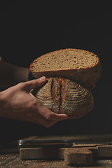 Image showing male baker holding in hands halves of fresh rye bread,