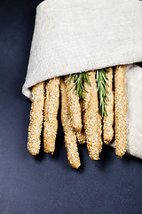 Image showing Italian grissini or salted bread sticks on linen napkin on black