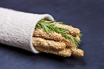 Image showing Italian grissini or salted bread sticks with rosemary herb on li