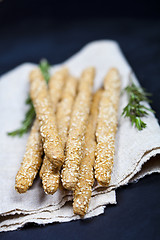 Image showing Italian grissini or salted bread sticks on linen napkin on black