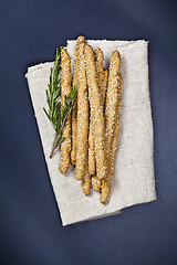 Image showing Italian grissini or salted bread sticks on linen napkin on black