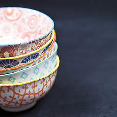 Image showing Stack of colorful empty ceramic bowls closeup on black board bac