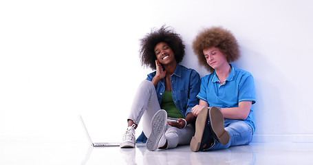 Image showing multiethnic couple sitting on the floor using a laptop and table