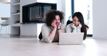 Image showing young multiethnic couple using a laptop on the floor