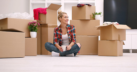 Image showing woman with many cardboard boxes sitting on floor