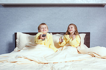 Image showing Happy laughing kids, boy and girl in soft bathrobe after bath play on white bed