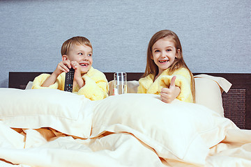 Image showing Happy laughing kids, boy and girl in soft bathrobe after bath play on white bed