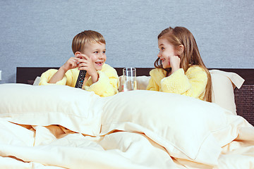 Image showing Happy laughing kids, boy and girl in soft bathrobe after bath play on white bed