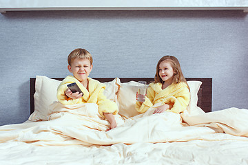 Image showing Happy laughing kids, boy and girl in soft bathrobe after bath play on white bed