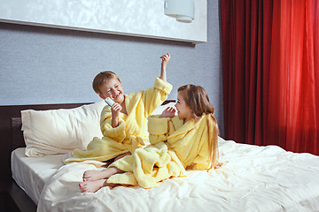 Image showing Happy laughing kids, boy and girl in soft bathrobe after bath play on white bed