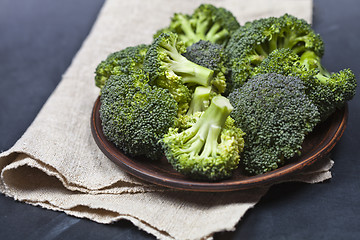 Image showing Fresh green organic broccoli in brown plate and linen napkin.