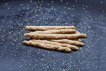Image showing Italian grissini or salted bread sticks with sesame seeds on bla