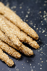 Image showing Italian grissini or salted bread sticks on linen napkin on black