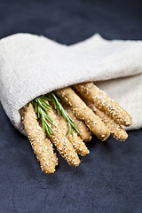 Image showing Italian grissini or salted bread sticks with rosemary herb on li