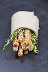 Image showing Italian grissini or salted bread sticks with rosemary herb on li