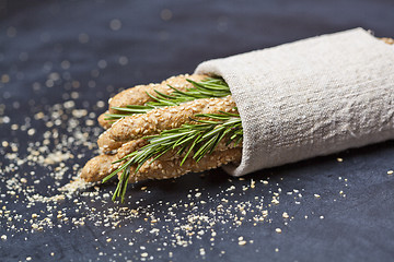 Image showing Italian grissini or salted bread sticks with rosemary herb on li