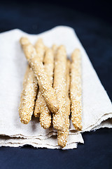 Image showing Italian grissini or salted bread sticks with sesame on linen nap