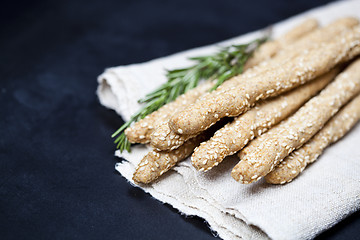 Image showing Italian grissini or salted bread sticks with rosemary herb on li