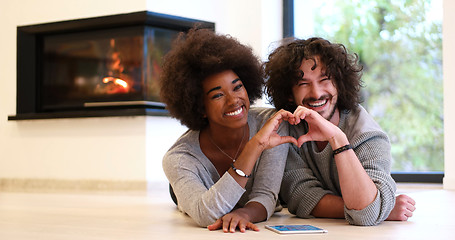 Image showing multiethnic couple showing a heart with their hands on the floor