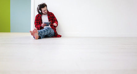 Image showing young man listenig music on tablet at home