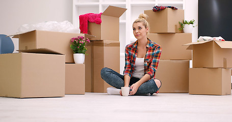 Image showing woman with many cardboard boxes sitting on floor