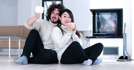 Image showing multiethnic romantic couple  in front of fireplace