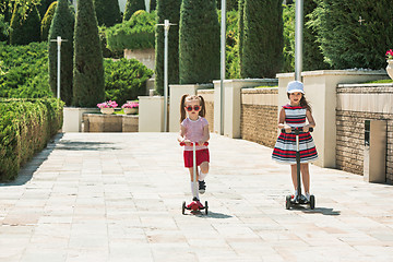 Image showing Preschooler girls riding scooter outdoors.