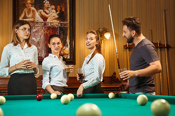 Image showing Young men and women playing billiards at office after work.