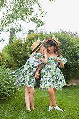 Image showing Portrait of smiling beautiful girls with hats against green grass at summer park.