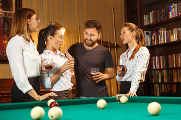 Image showing Young men and women playing billiards at office after work.