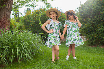 Image showing Portrait of smiling beautiful girls with hats against green grass at summer park.