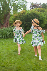 Image showing Portrait of smiling beautiful girls with hats against green grass at summer park.