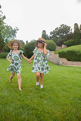 Image showing Portrait of smiling beautiful girls with hats against green grass at summer park.