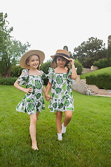 Image showing Portrait of smiling beautiful girls with hats against green grass at summer park.