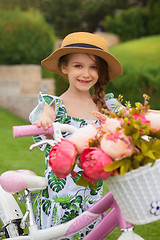 Image showing Beautiful little girl riding a bicycle through the park. Nature, lifestyle