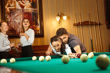 Image showing Young men and women playing billiards at office after work.