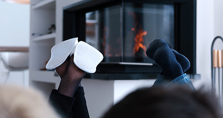 Image showing Young couple sitting in front of fireplace