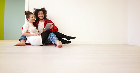 Image showing Young Couple using digital tablet on the floor