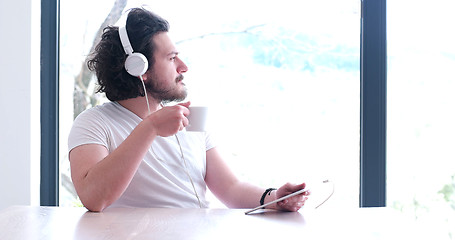 Image showing young man listenig music on tablet at home